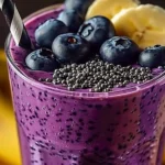 Banana Blueberry Smoothie in a glass, garnished with fruit.