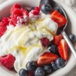 A bowl of dry yogurt topped with colorful fruit powder and granola.