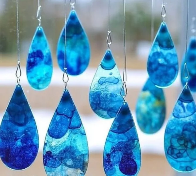Blue Crayon Raindrop Suncatchers glowing in sunlight, creating colorful reflections.