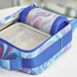 A person placing a lunch box in a washing machine for cleaning.