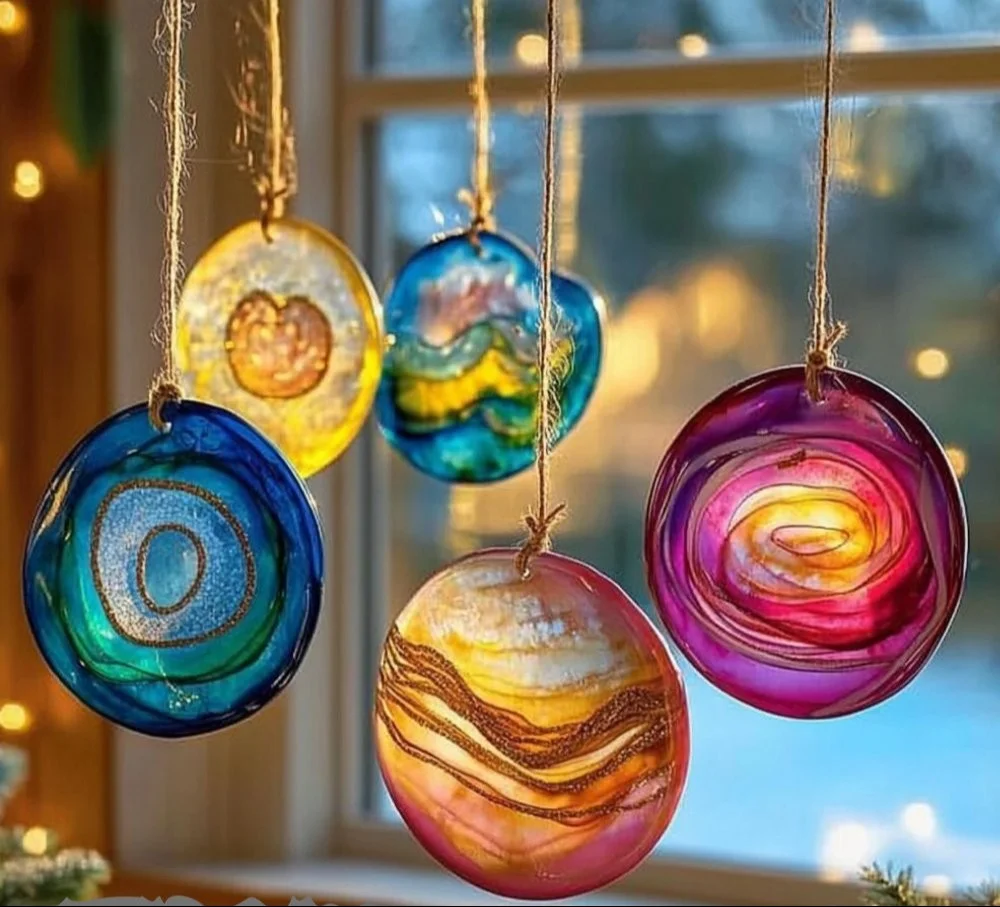 Handmade DIY glue suncatchers in bright colors hanging in a window.