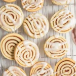 Freshly baked irresistible cinnamon roll cookies with gooey filling and cream cheese frosting.