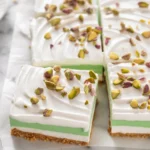 Layered pistachio dessert with whipped cream and chopped pistachios on top.