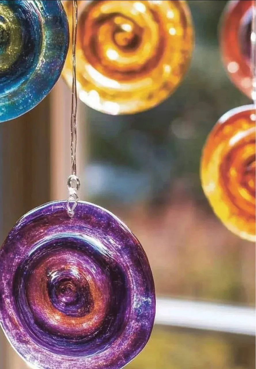 Colorful tie-dye glue suncatchers hanging in sunlight.